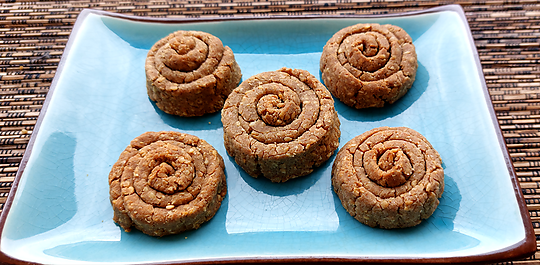 "Espirals de Fajol i Gomasi acabades de sortir del forn, daurades i cruixents, servides en un plat de ceràmica."